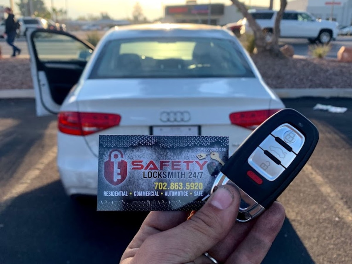 Technician holding a newly cut transponder car key in front of a white car