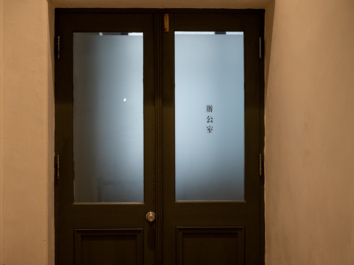 Dark double entrance doors with frosted glass panels on a commercial suite