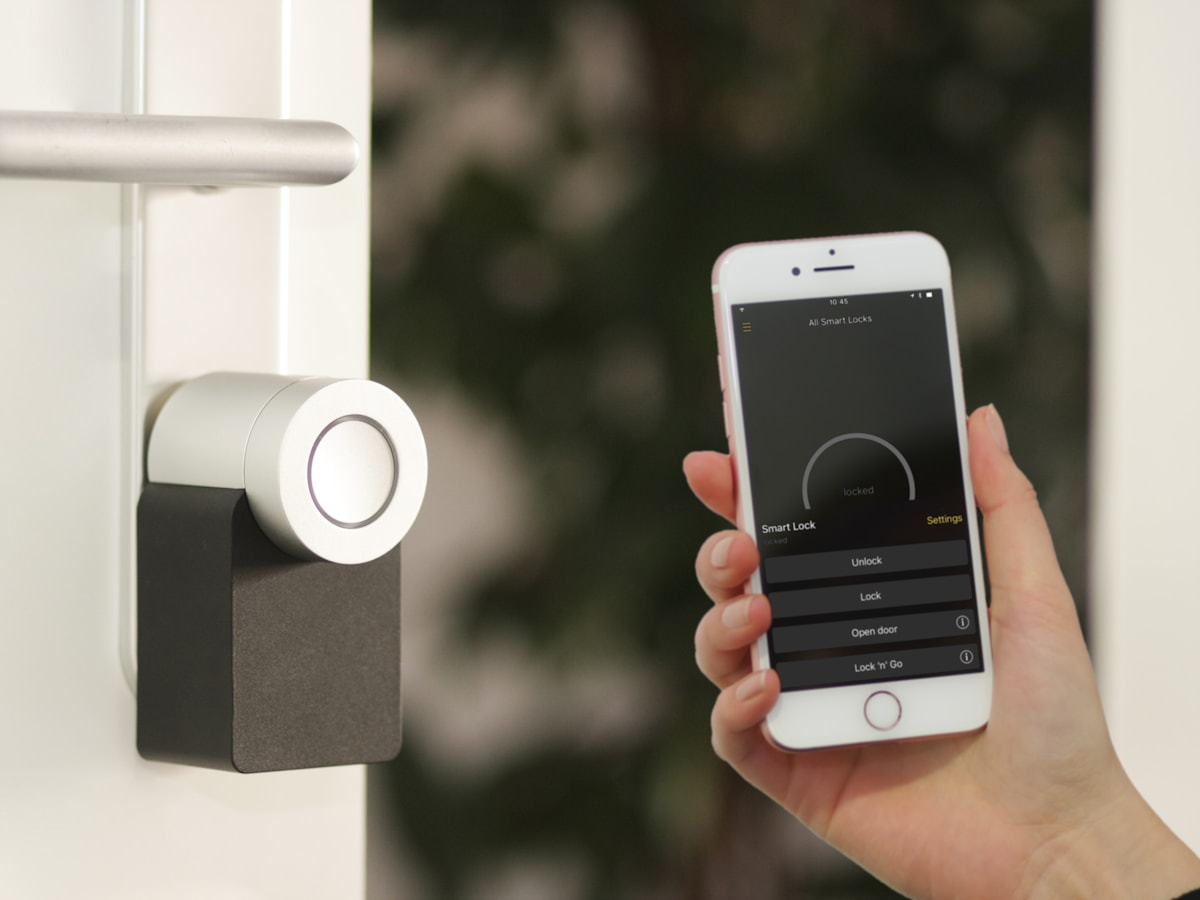 Homeowner unlocking an app-controlled smart deadbolt with a phone at the front door